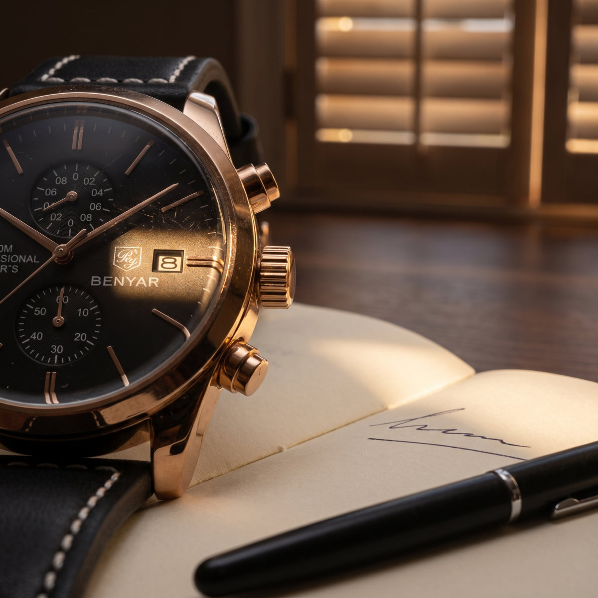 Livorno with rose gold-tone case and black dial resting on an open notebook beside a fountain pen