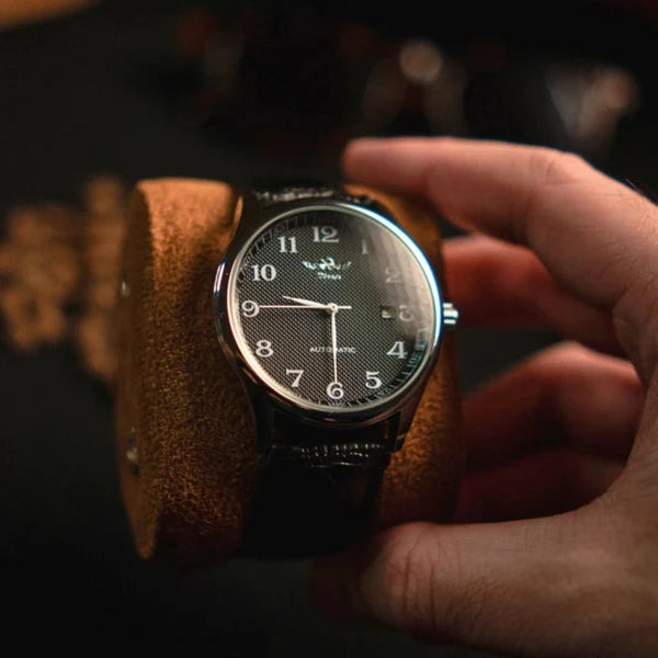 Lorenzo black dial watch on a suede watch pillow, railroad minute track in view
