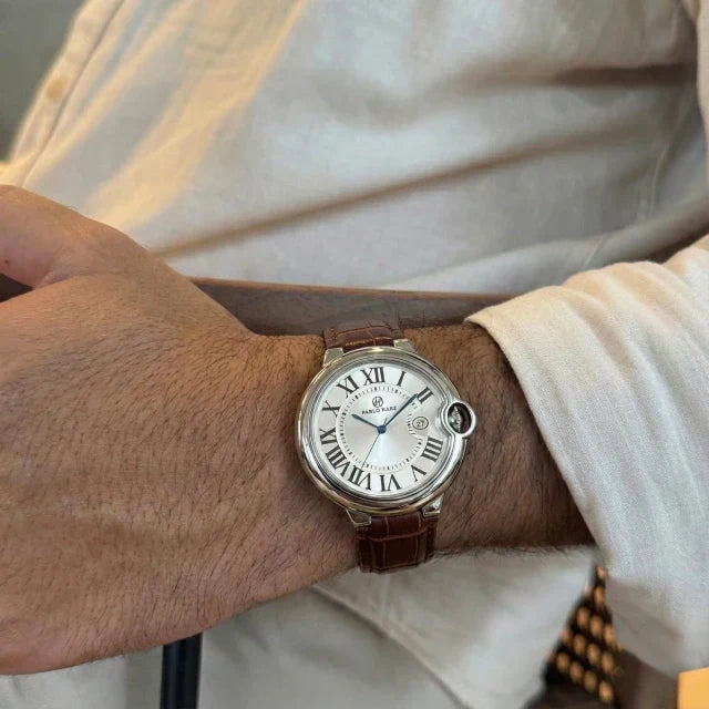 Classic steel watch on a brown leather strap worn under a linen shirt cuff in warm light