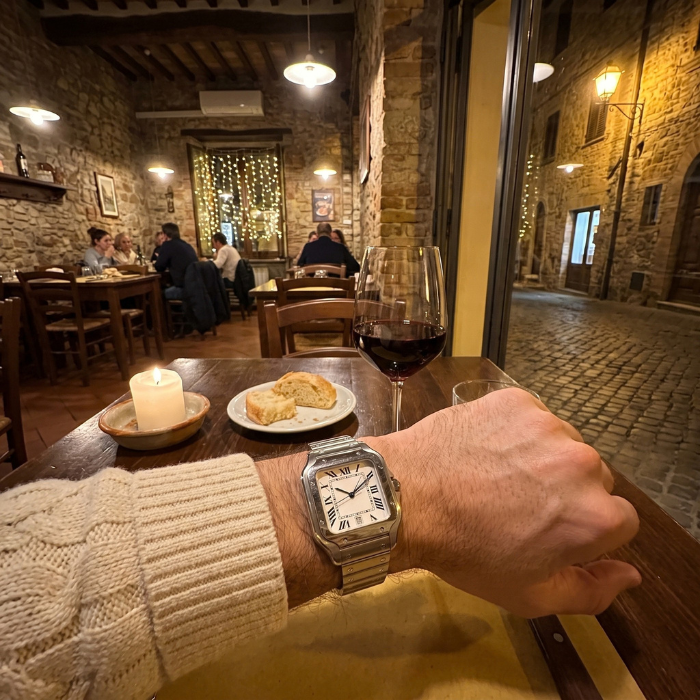 Santtus square watch with Roman numeral dial and steel bracelet worn at a candlelit tavern table with red wine and bread