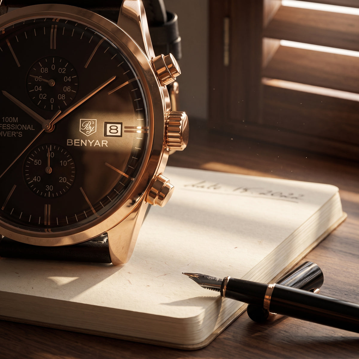 Macro of the Livorno's rose gold-tone case and black dial with two sub-dials beside a fountain pen