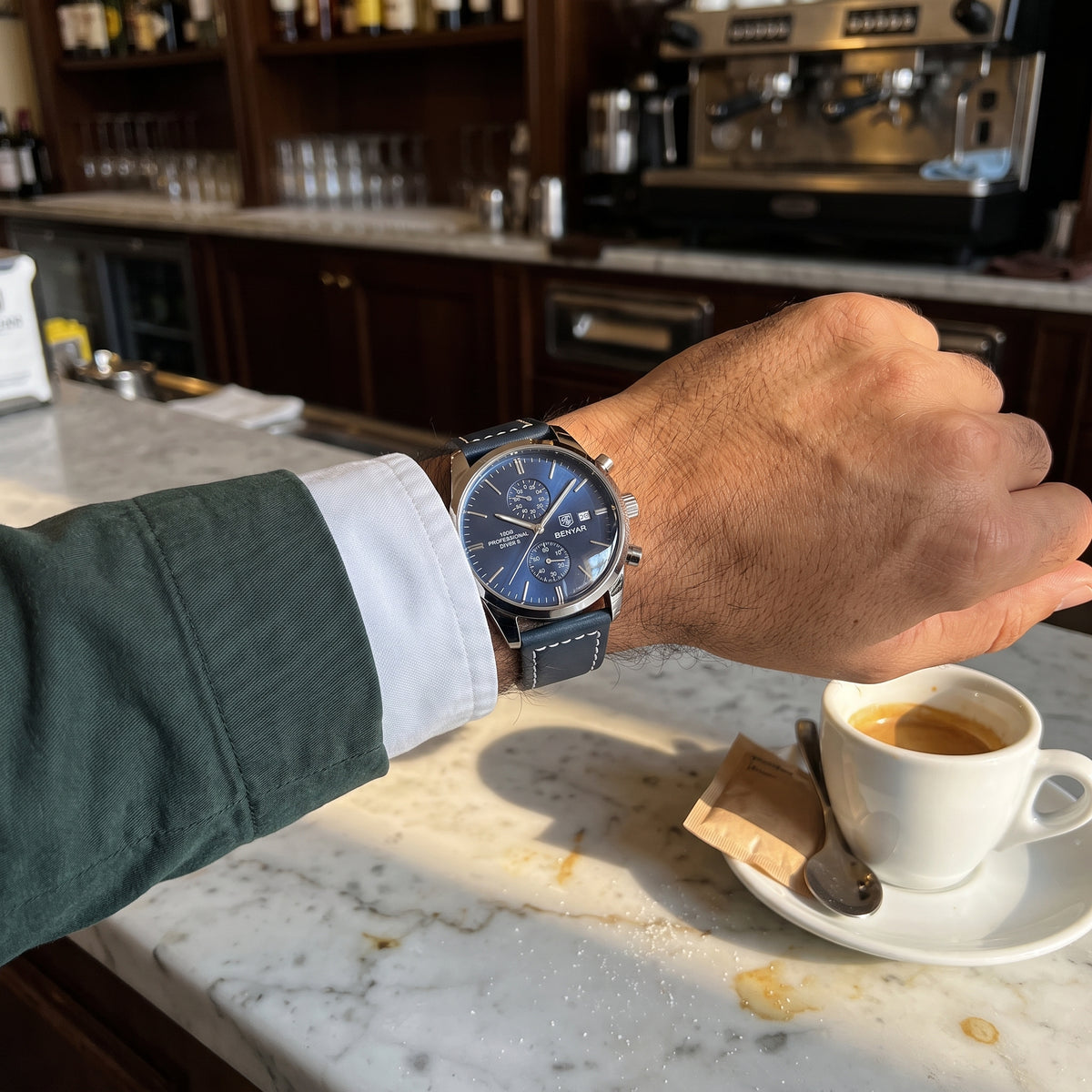 Livorno watch with silver-tone case, deep blue dial and blue leather strap worn on the wrist at a cafe counter