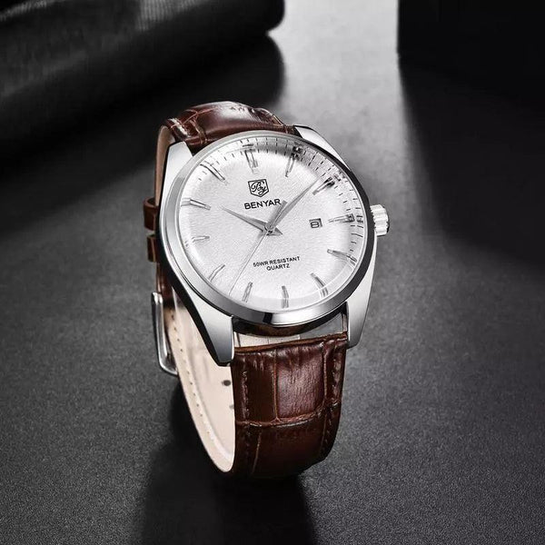 Lucca watch in pearl white and brown leather resting on a dark desk surface, showing the slim steel case profile