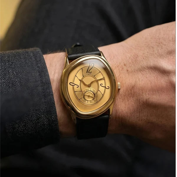 Gold tone Tiziano watch on black leather worn with a charcoal jacket